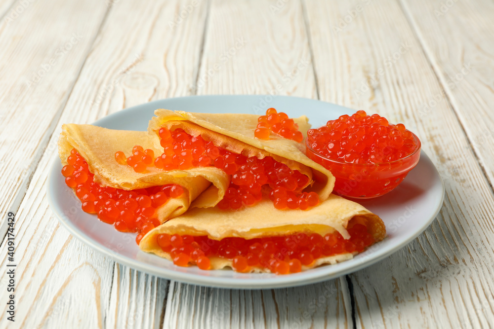 Plate of crepes with red caviar on white wooden background Plate of crepes with red caviar on white wooden background