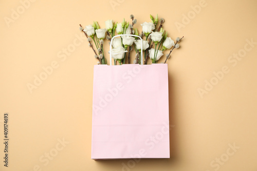 Pink paper bag with roses and willow catkins on beige background