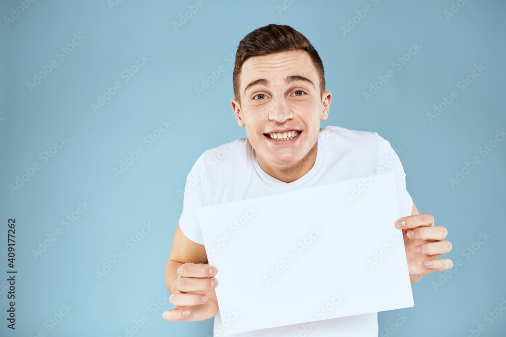 man holding a sheet of paper in his hands white t-shirt cropped view blue background man holding a sheet of paper in his hands white t-shirt cropped view blue background