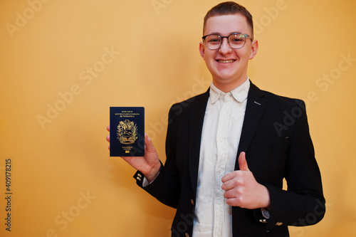 Young handsome man holding Bolivarian Republic of Venezuela passport id over yellow background, happy and show thumb up. Travel to America countries. photo