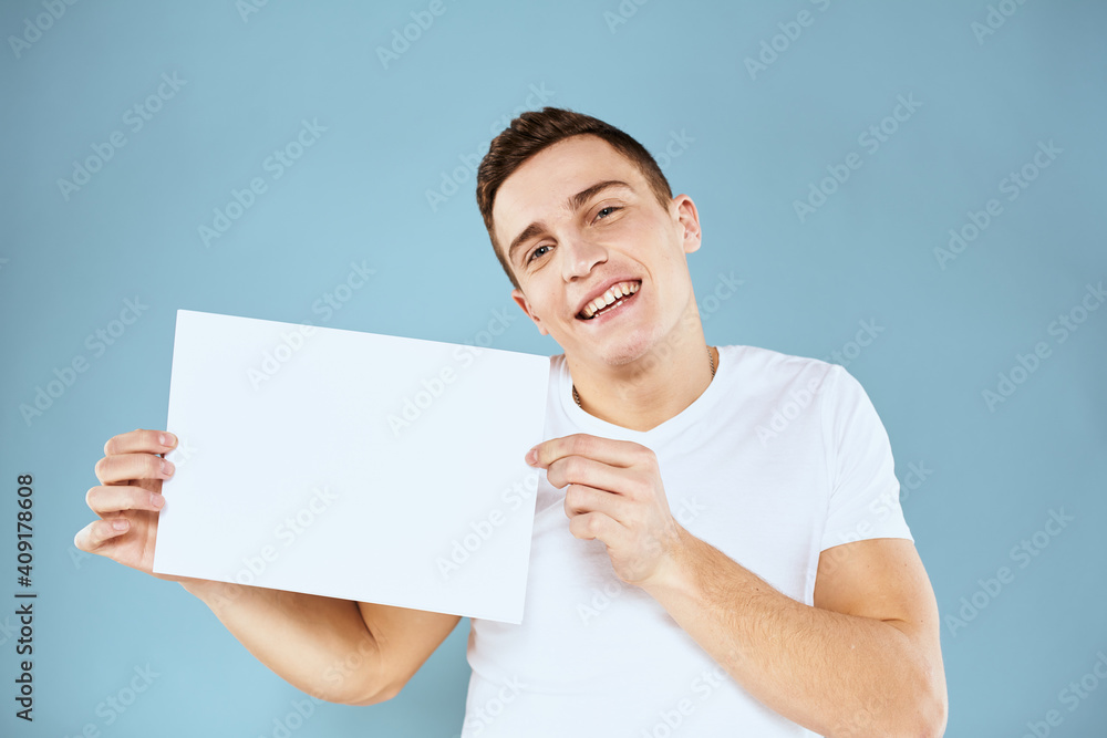 man holding a sheet of paper in his hands white t-shirt cropped view blue background man holding a sheet of paper in his hands white t-shirt cropped view blue background