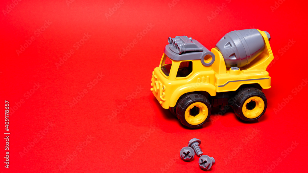 Obraz premium Toy on a red background. A boy's car with a place for text for a toy store. Disassembled typewriter on screws with screwdriver