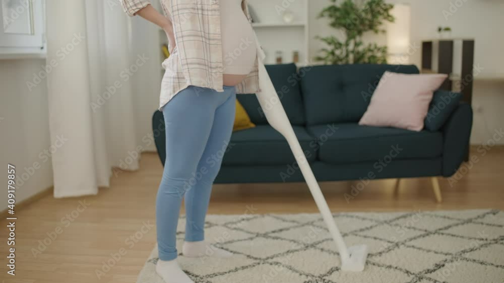 Young pregnant female with belly suffering from back ache, cleaning house, rest Young pregnant female with belly suffering from back ache, cleaning house, rest