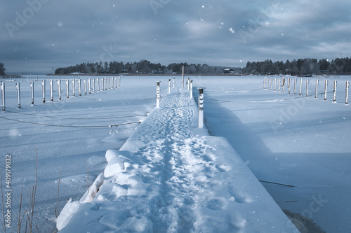 Snow covered pier on frozen sea. White winter landscape. Naantali, Finland. photo