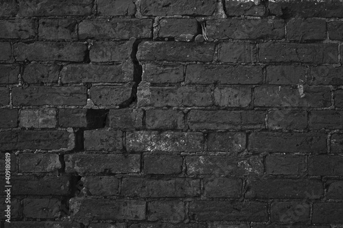 Dark Brick Wall With Big Crack Structure. Damaged Brickwork Surface Texture. Destroyed And Aged Old Bricklaying Rift Material.
