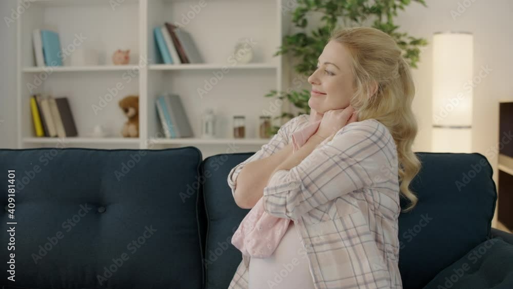 Glad pregnant woman holding newborn bodysuit, happiness of expecting, childbirth Glad pregnant woman holding newborn bodysuit, happiness of expecting, childbirth