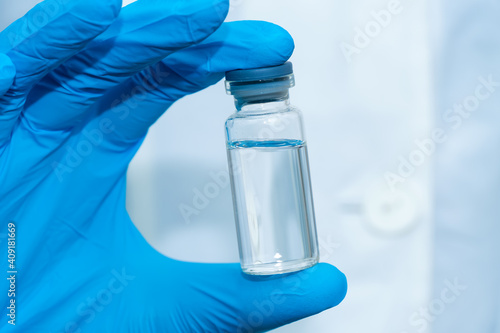 Doctor's hand in blue gloves holds a medical bottle with a medicine close-up. Concept of medicine