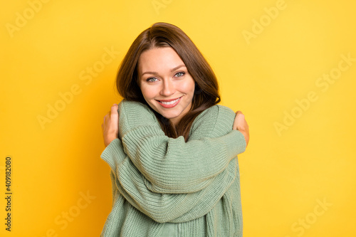 Photo portrait of girl hugging self in warm sweater isolated on vivid yellow colored background © deagreez