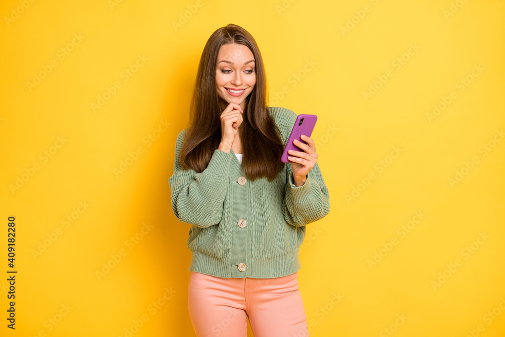 Photo portrait of smiling woman touching face chin with finger holding phone in one hand isolated on vivid yellow colored background Photo portrait of smiling woman touching face chin with finger holding phone in one hand isolated on vivid yellow colored background