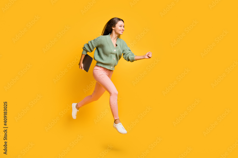 Full size profile side photo of young pretty happy business woman run in air with laptop in hand isolated on yellow color background