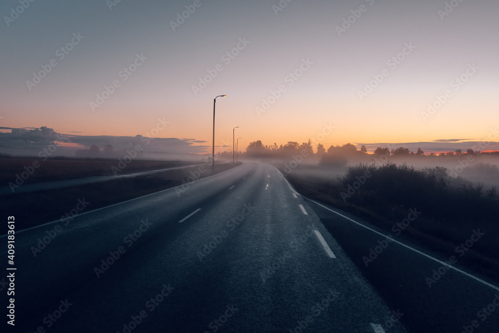Rural country road on a foggy morning at sunrise.