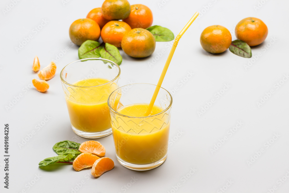 Fototapeta premium Two glasses with citrus juice, straws in glass. Tangerines on table