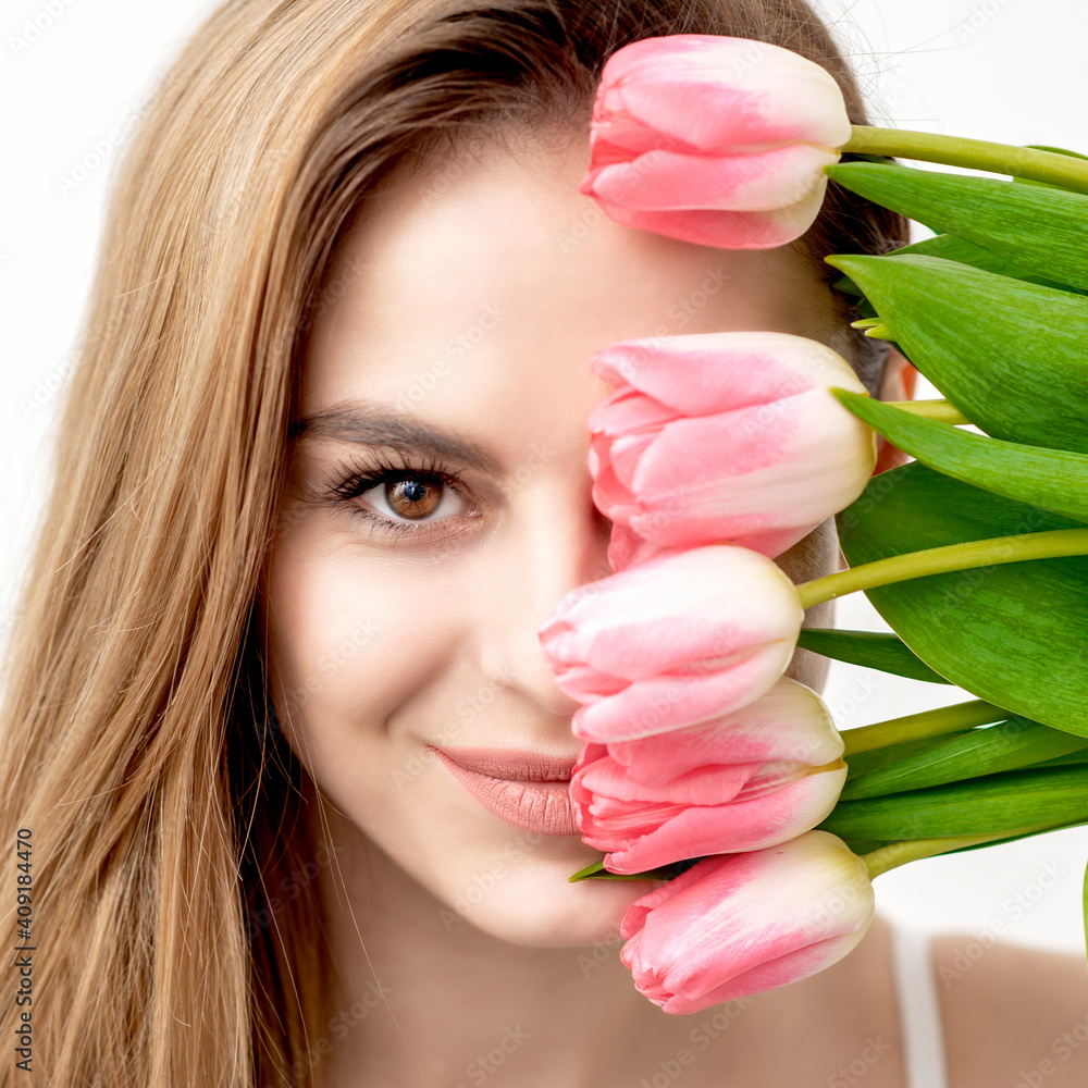 Portrait of a happy young caucasian woman with pink tulips against a white background Portrait of a happy young caucasian woman with pink tulips against a white background