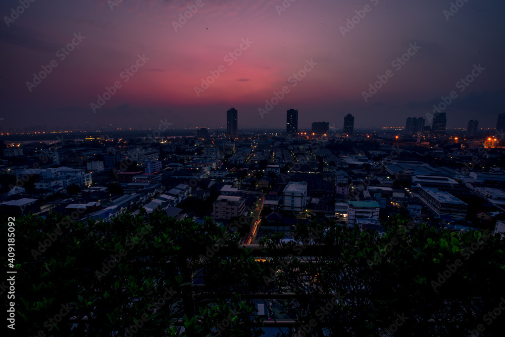 Obraz premium The high angle background of the city view with the secret light of the evening, blurring of night lights, showing the distribution of condominiums, dense homes in the capital community