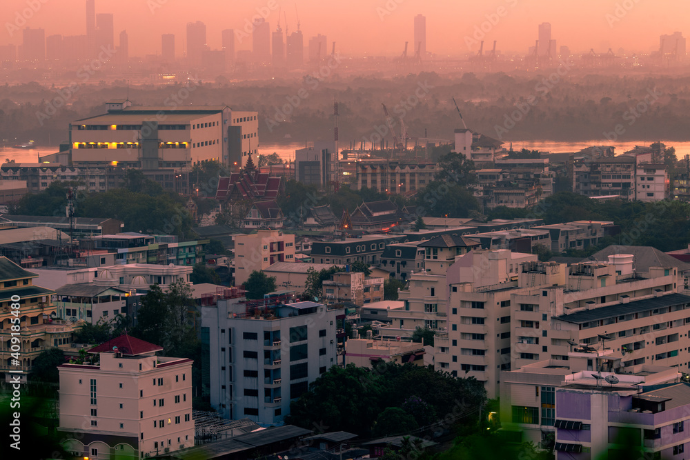 Naklejka premium The high angle background of the city view with the secret light of the evening, blurring of night lights, showing the distribution of condominiums, dense homes in the capital community