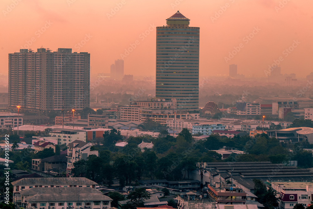 Fototapeta premium The high angle background of the city view with the secret light of the evening, blurring of night lights, showing the distribution of condominiums, dense homes in the capital community