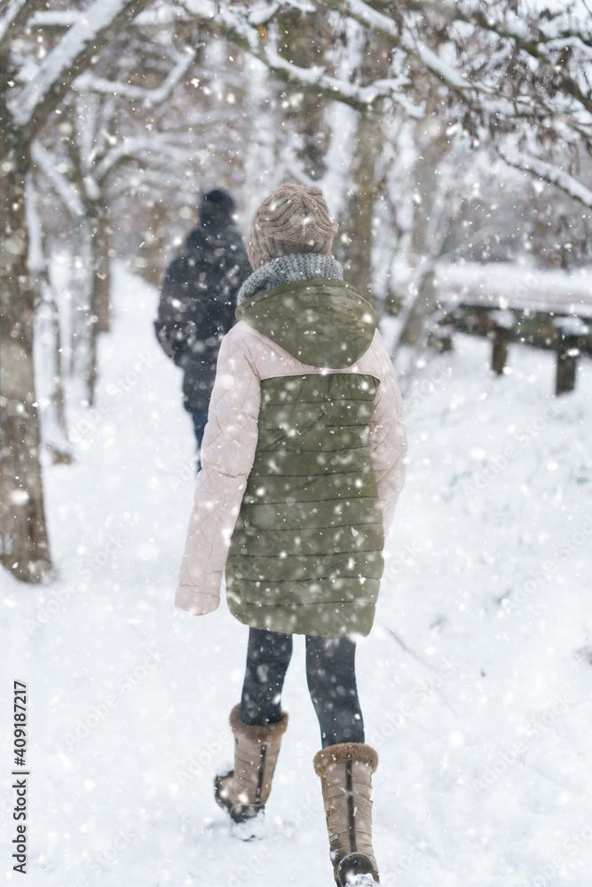 two people walk on a snow-covered path in winter, a teenage boy and a girl, a snowstorm two people walk on a snow-covered path in winter, a teenage boy and a girl, a snowstorm