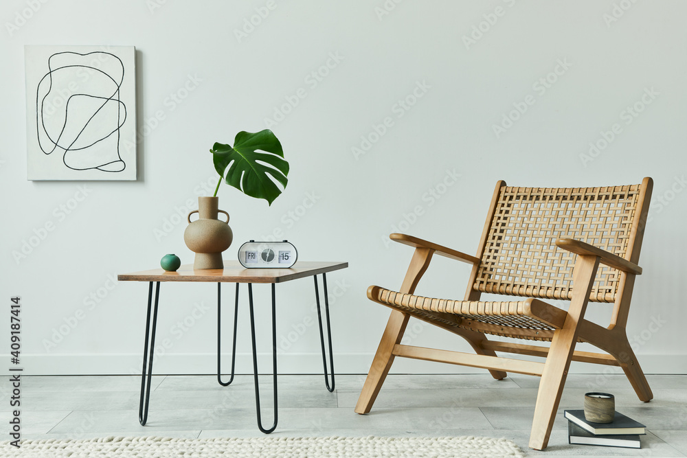 Fototapeta premium Minimalist concept of living room interior with rattan armchair, walnut coffee table, tropical leaf in vase, clock, mock up painintgs, books and personal accessories in stylish home decor. Template.