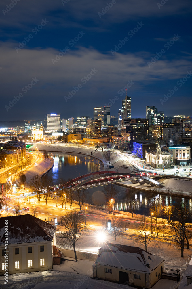 Obraz premium Vilnius, capital of Lithuania, beautiful scenic aerial panorama of modern business financial district architecture buildings with river and bridge in winter, vertical