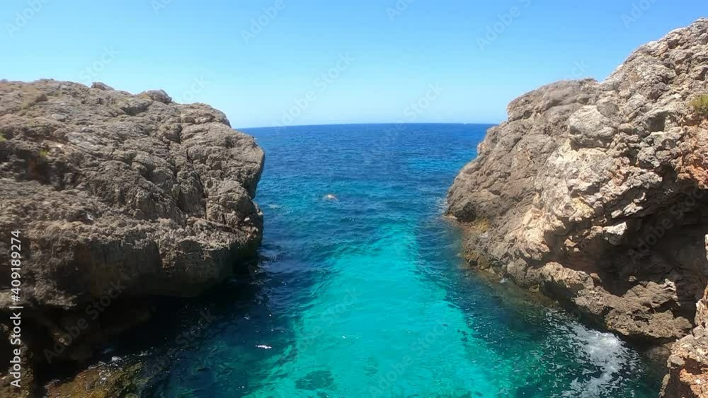Young man swimming on the coast of mallorca with beaturiful view of the sea with crystalclear water. Sea view of tourquise colour. Concept of summer, travel, relax and enjoy Young man swimming on the coast of mallorca with beaturiful view of the sea with crystalclear water. Sea view of tourquise colour. Concept of summer, travel, relax and enjoy