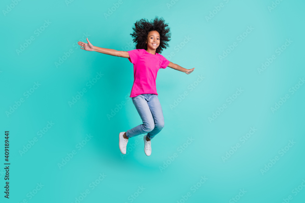 Full size photo of young happy positive good mood charming girl jumping hold hands wings isolated on turquoise color background Full size photo of young happy positive good mood charming girl jumping hold hands wings isolated on turquoise color background
