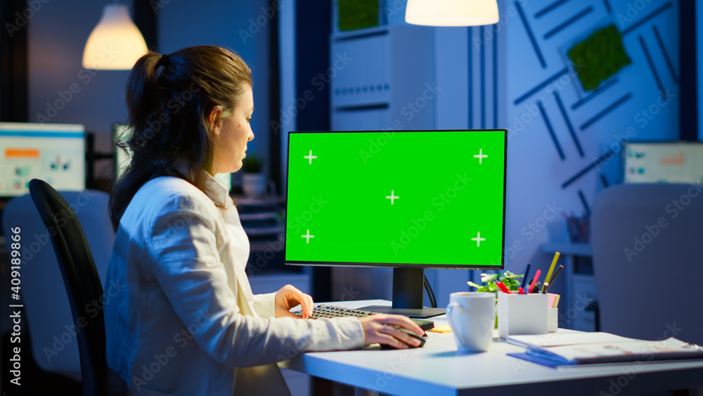 Woman looking at computer with chroma key during night time in start up business office working overtime. Freelancer watching desktop monitor mockup display with green screen, typing writting Woman looking at computer with chroma key during night time in start up business office working overtime. Freelancer watching desktop monitor mockup display with green screen, typing writting