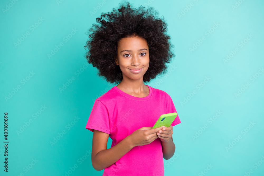 Photo portrait of positive black skin girl holding phone in two hands isolated on vivid cyan colored background