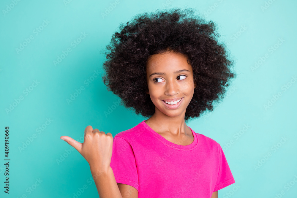 Photo portrait of afro american girl pointing finger looking behind back at blank space isolated on vivid cyan colored background Photo portrait of afro american girl pointing finger looking behind back at blank space isolated on vivid cyan colored background