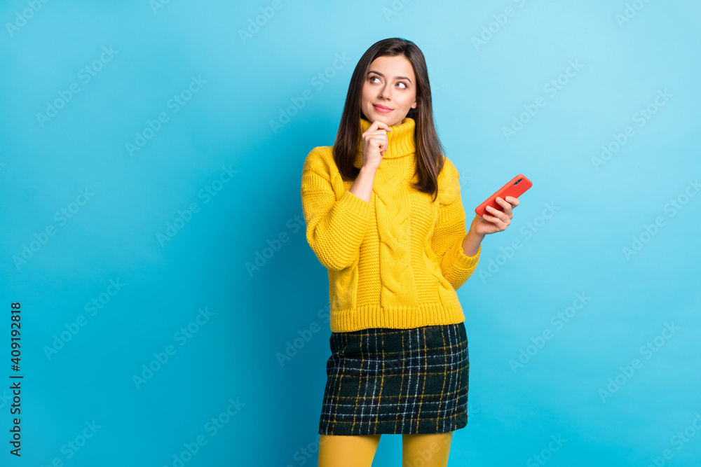 Portrait of pretty cheery minded girl using gadget thinking copy space isolated over bright blue color background Portrait of pretty cheery minded girl using gadget thinking copy space isolated over bright blue color background