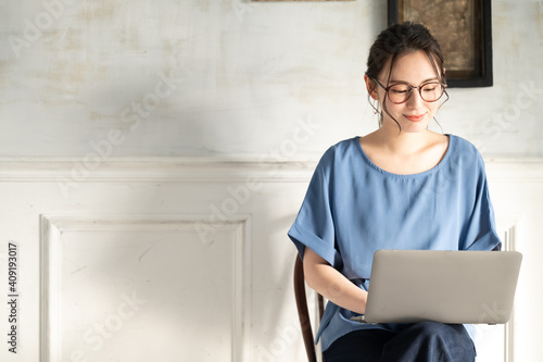 A young Japanese woman with beautiful smiling glasses having a remote work meeting using a computer. Vertical copy space available photo