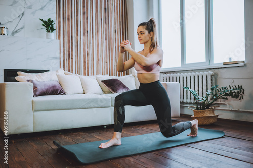 Foto Young fit woman do frontal lunges or squat exercise indoors in living room