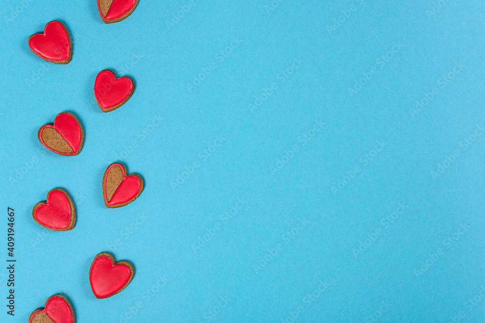 Valentines day, red cookies in shape of heart  on left side of  blue paper background, flat lay. Love and Valentine's day concept.