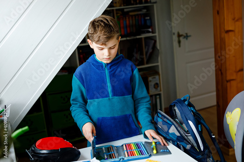 School kid boy getting ready in the morning for school. Healthy child filling satchel with books, pens, folders and school stuff. Preaparation, routine concept. photo