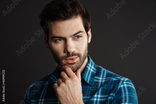 Pleased handsome unshaven guy posing and looking aside