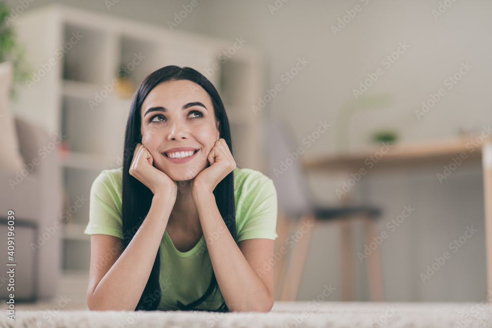 Close-up portrait of lovely cheery creative long-haired girl lying on carpet thinking creating solution at light interior room Close-up portrait of lovely cheery creative long-haired girl lying on carpet thinking creating solution at light interior room
