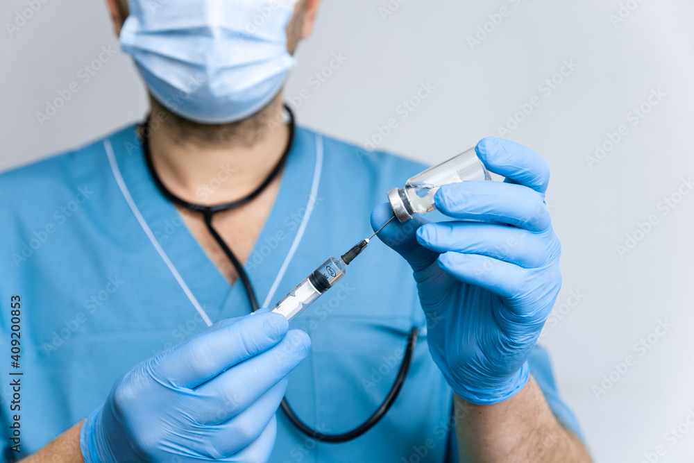 Doctor with blue surgical gloves dials a coronavirus vaccine into a syringe to vaccinate against a worldwide epidemic coronavirus covid-19. Healthcare And Medical concept Doctor with blue surgical gloves dials a coronavirus vaccine into a syringe to vaccinate against a worldwide epidemic coronavirus covid-19. Healthcare And Medical concept