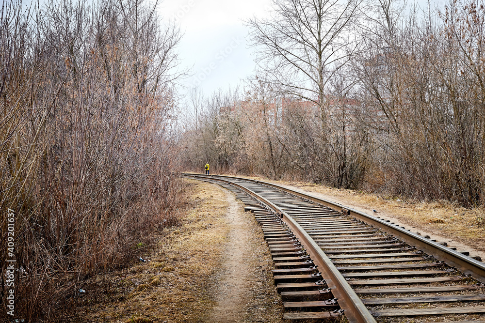 Railway among bare and bald trees on an autumn or spring day