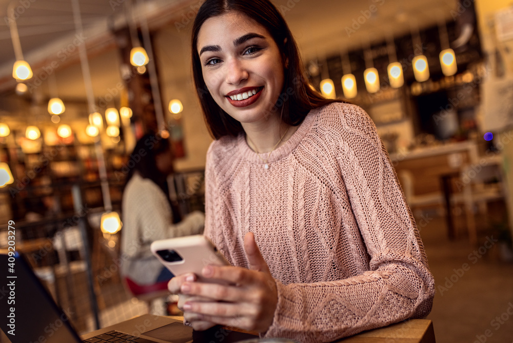 Portrait of young woman using smartphone in coffee shop. Portrait of young woman using smartphone in coffee shop.