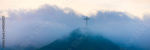 Obraz na płótnie A single cross stands on a mountain engulfed in white clouds w salonie