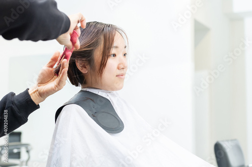 ヘアサロンで髪の毛をカットしてもらう若い女性