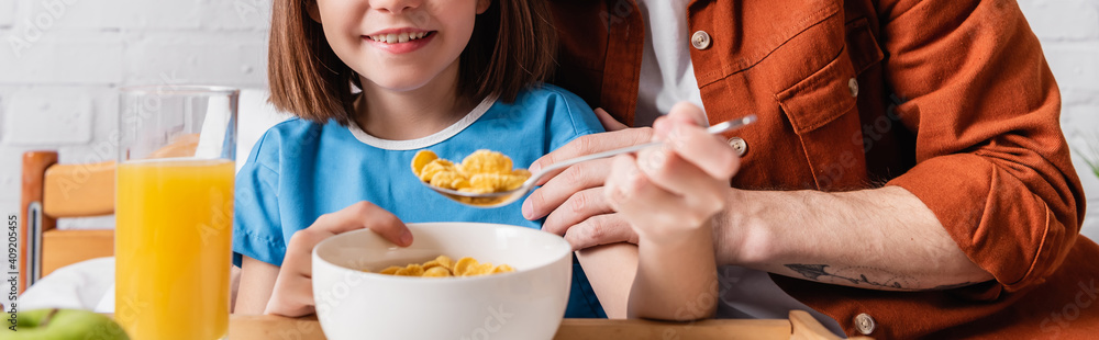 cropped view of father feeding daughter with cornflakes in hospital, banner cropped view of father feeding daughter with cornflakes in hospital, banner