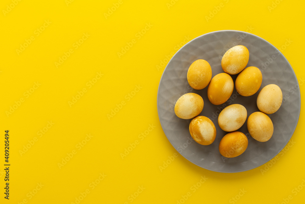 Easter golden painted eggs in gray plate on yellow background, easter festive concept Easter golden painted eggs in gray plate on yellow background, easter festive concept