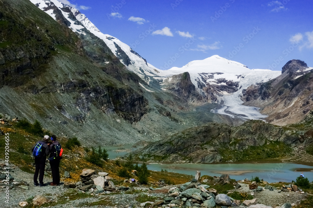 two hikers talking at a place in the mountains with snow and a glacier