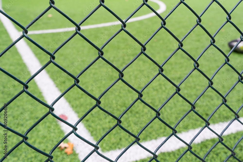 Fototapeta premium Fence netting close-up on a background of a soccer field.