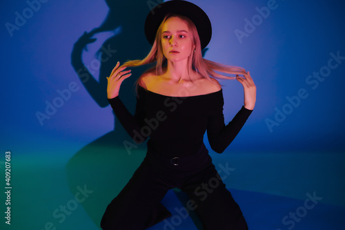 Beautiful young girl in colourful neon light on blue background. © eduard