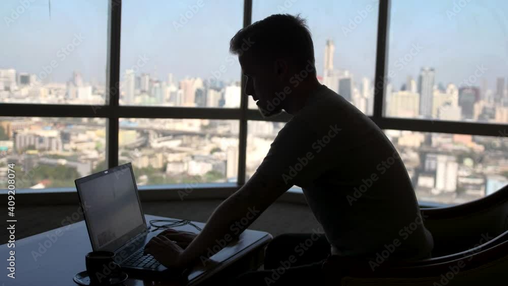 custom made wallpaper toronto digitalA concentrated young businessman is working on a laptop computer using his notebook sitting by the window with urban view and drinks coffee