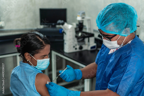 Physician injecting a Latina woman with covid 19 vaccine.