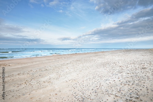 Fototapeta Naklejka Na Ścianę i Meble -  Panoramic view of the Baltic sea from a sandy shore (sand dunes). Dramatic sky with glowing clouds, waves and water splashes. Idyllic seascape. Warm winter weather, climate change, nature. Denmark
