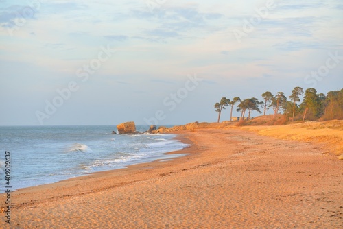 Baltic sea shore (sand dunes) at sunset. Soft sunlight, clear sky, glowing clouds, waves. Idyllic seascape. Ziemelu Mols, Liepaja, Latvia, Europe. Travel destinations, ecotourism, nature photo