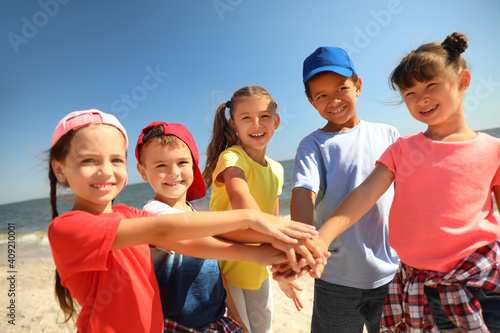 Photography Group of children putting hands together at sea beach on sunny day